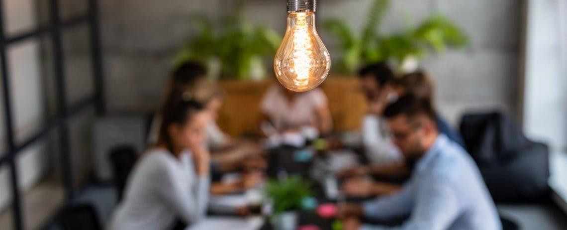 Overlegsituatie aan tafel met gloeilamp op de voorgrond