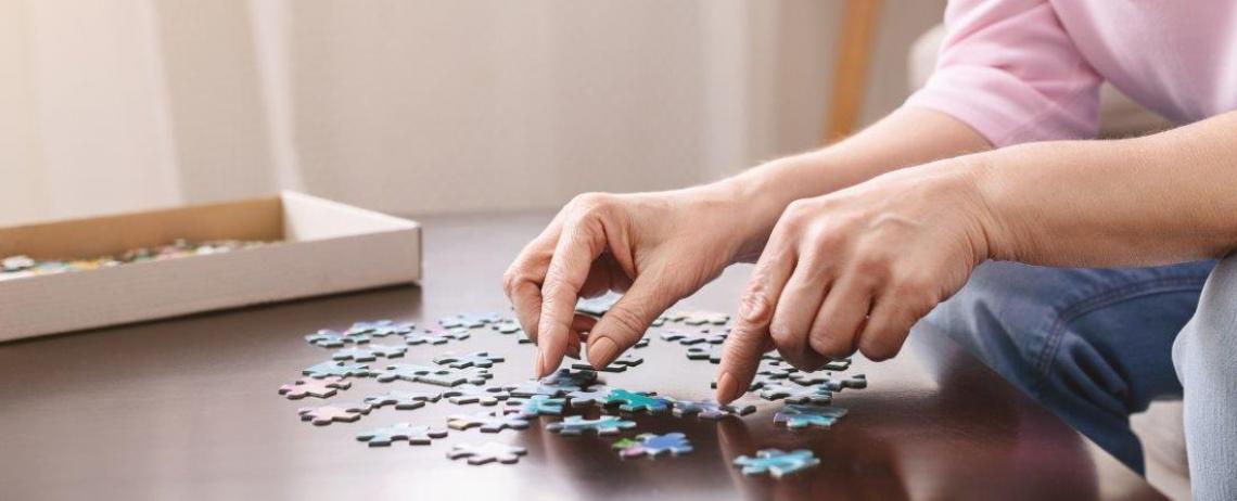 Vrouw is bezig met puzzel aan tafel