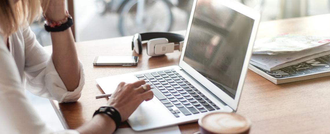 Vrouw zoekt informatie op laptop aan tafel met kop koffie