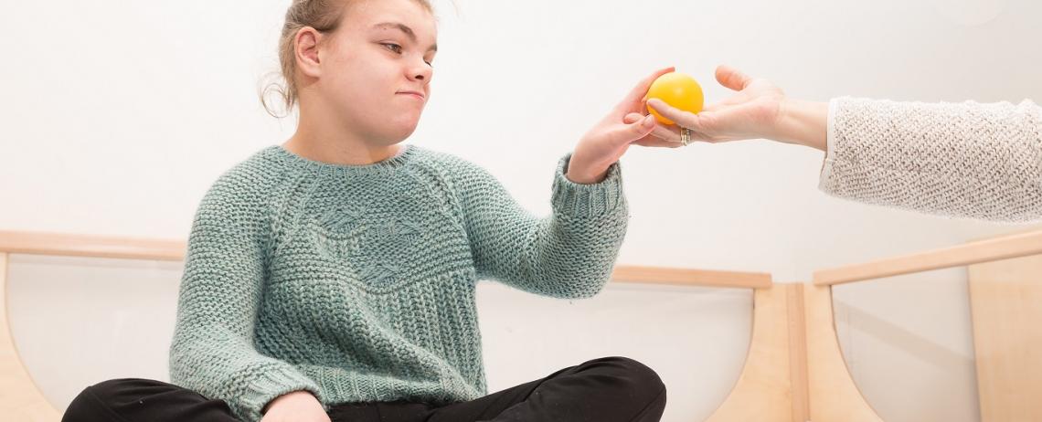 Meisje op bed geeft bal aan begeleider