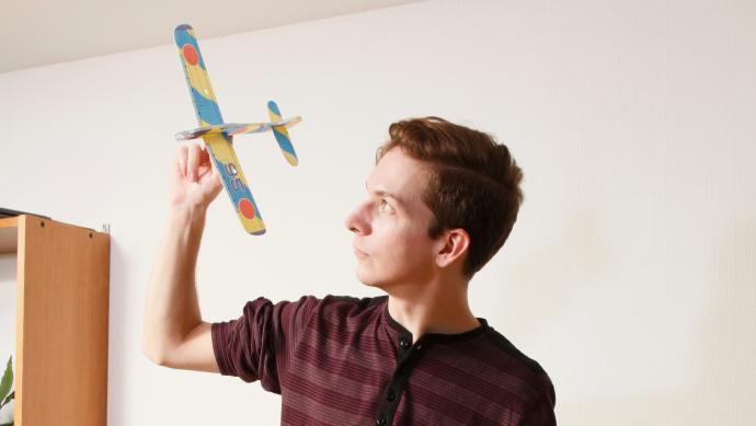 Man met papieren vliegtuig in zijn hand