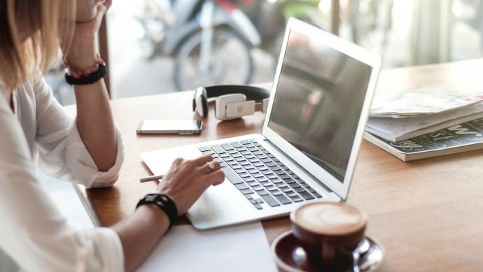 Vrouw zoekt informatie op laptop aan tafel met kop koffie
